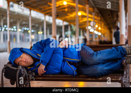 Banc passager man sleeping on at train station Banque D'Images