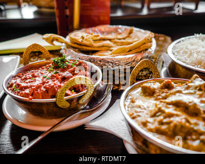 La nourriture indienne ou indien Curry dans un cuivre laiton servant bol oriental, des morceaux de filet de poulet au curry ingrédients de la sauce dans une casserole avec l'ancienne table Banque D'Images
