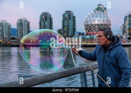 Le centre-ville de Vancouver, Colombie-Britannique, Canada - le 29 novembre 2018 : l'homme fait de grosses bulles de savon à False Creek pendant un coucher de soleil. Banque D'Images