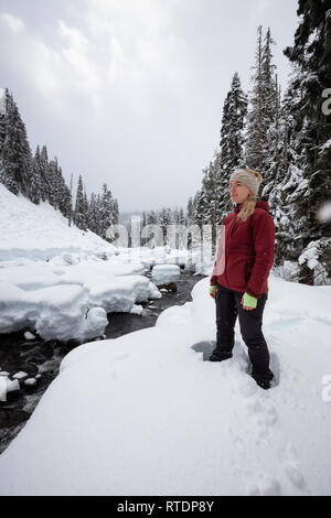 Caucasian girl blonde profite des beaux paysages d'hiver du Canada au cours d'un jour de neige. Pris dans Alexander Falls, près de Whistler et de Squamish, Nort Banque D'Images