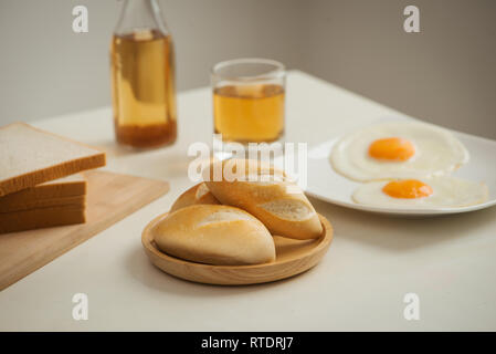 Le petit déjeuner du matin avec verre de thé, toasts, œufs sur le plat et du pain sur la table Banque D'Images