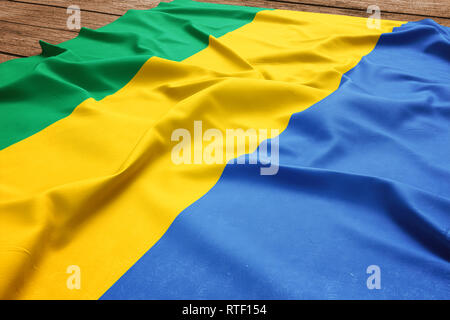 Pavillon du Gabon sur un bureau en bois. Drapeau gabonais soie vue d'en haut. Banque D'Images