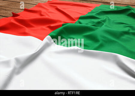 Pavillon de Madagascar sur un bureau en bois. Drapeau malgache soie vue d'en haut. Banque D'Images