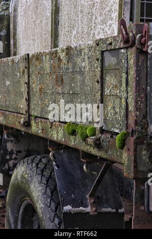 Moss pousse sur un vieux agricultural land rover avec côtés en bois, comme il se décompose lentement dans un champ d'agriculteurs. Banque D'Images