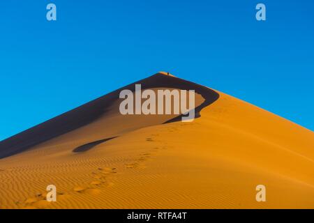 Femme marche vers le haut de la Dune 45 sanddune géant, Namib-Naukluft National Park, Namibie Banque D'Images