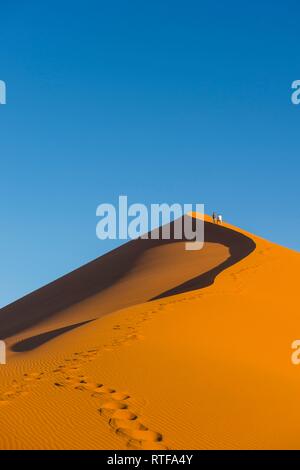 Femme marche vers le haut de la Dune 45 sanddune géant, Namib-Naukluft National Park, Namibie Banque D'Images