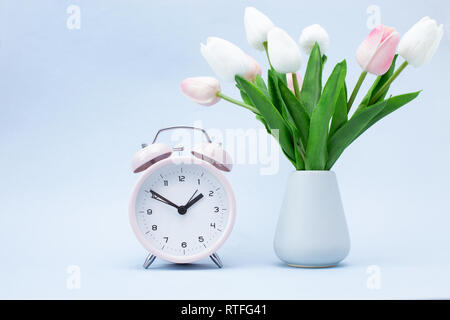 Réveil rose et un bouquet de fleurs sur fond bleu le Printemps ! Banque D'Images