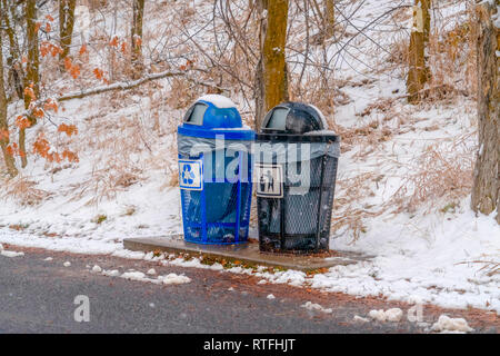 Les poubelles près d'une route et pente enneigée. Extérieur noir et bleu les poubelles placées sur le bord d'une route. Arbres sur un couvert de neige peut être slopw voir Banque D'Images