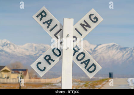 Railroad Crossing sign contre une montagne enneigée. Un panneau de passage à niveau du chemin de fer en bois vue sur une journée ensoleillée. Une montagne de neige et ciel immense c Banque D'Images