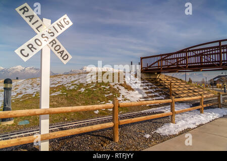 Railroad Crossing sign bridge et contre la montagne. Railroad Crossing panneau près d'une voie ferrée qui passe sous un pont. Montagnes couvertes de neige et Banque D'Images