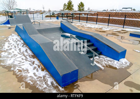 Rampe de skate avec de la neige fondue sur une journée ensoleillée. Des rampes de skate sur un skate parc avec la fonte de la neige au sol. Dans l'arrière-plan sont des maisons et Banque D'Images