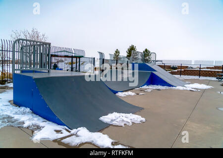 Rampes de planche à roulettes et la fonte de la neige sur un skate park. Skate park avec la fonte de la neige autour de la rampe de skate. Dans l'arrière-plan est un hiver paysag Banque D'Images