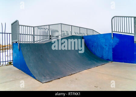 Rampe de skate avec la neige et le fond de ciel. Une pente raide sur une rampe de skate skate park avec ciel sans bornes à l'arrière-plan. Un paysage couvert Banque D'Images