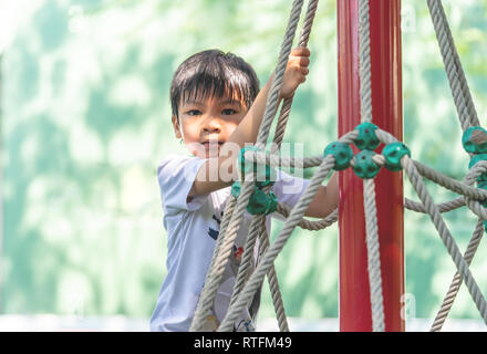 Asian boy est l'escalade sur le poteau de corde en aire de jeux Banque D'Images