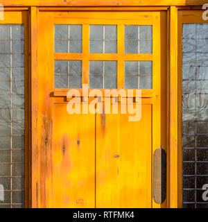 Porte en bois ensoleillée avec des panneaux de verre. Le soleil brille sur la porte en bois d'un bâtiment. Reflet des arbres et du ciel peut être se Banque D'Images