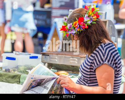 ARUTANGA, Aitutaki, ÎLES COOK - 30 septembre 2018 : une couronne de fleurs en lisant un journal sur une rue de la ville. Avec selective focus Banque D'Images