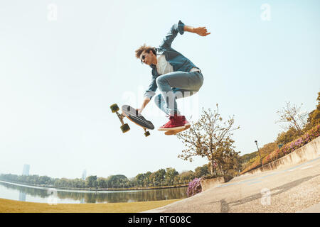 Hipster homme saute avec roulettes dans park Banque D'Images