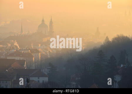 Matin d'hiver dans la région de Mala Strana - partie historique de Prague, en République tchèque. Église Saint Nicolas. Le lever du soleil. Le brouillard. Vue depuis le monastère de Strahov. Banque D'Images