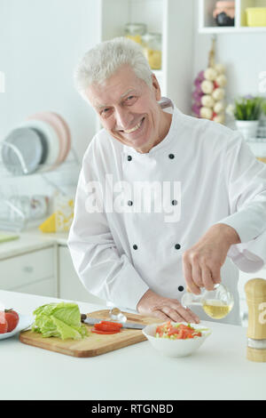 Portrait of elderly male chef versez de l'huile dans la salade Banque D'Images