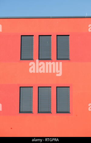 Fenêtre avec stores volets sombre sur un mur de la maison rouge Banque D'Images