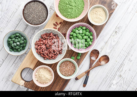 Super-aliments différents dans des bols en bois blanc sur l'arrière-plan, Vue de dessus Banque D'Images