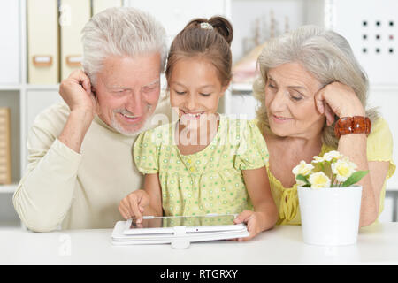 Portrait de grands-parents avec sa petite-fille à l'aide de tablet Banque D'Images