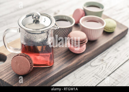 Différentes sortes de macarons à théière en verre tasses et gros plan sur fond de bois Banque D'Images