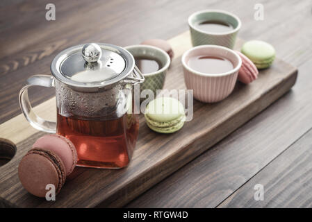 Différentes sortes de macarons à théière en verre tasses et gros plan sur fond de bois Banque D'Images