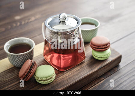 Différentes sortes de macarons à théière en verre tasses et gros plan sur fond de bois Banque D'Images