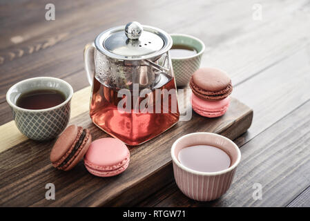 Différentes sortes de macarons à théière en verre tasses et gros plan sur fond de bois Banque D'Images