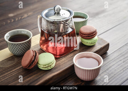 Différentes sortes de macarons à théière en verre tasses et gros plan sur fond de bois Banque D'Images