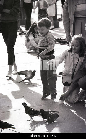 Années 1970, Trafalgar Square, Londres, excité les jeunes enfants nourrir les pigeons. Ces oiseaux sauvages utilisées pour flock à la place au grand amusement pour les nombreux visiteurs, avant que les nouveaux règlements mis en place en 2001 a les nourrir une infraction. Banque D'Images