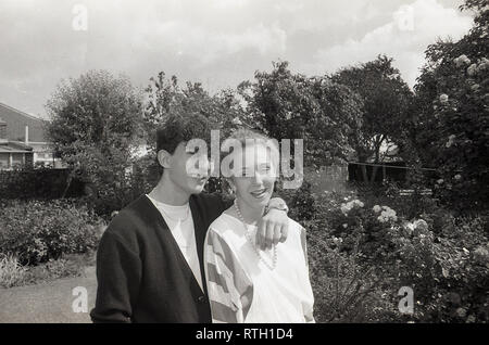 Datant des années 1970, et dans l'amour, un vieux couple ensemble dans une banlieue anglaise jardin arrière, England, UK. Banque D'Images