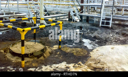 L'huile renversée sur un sol sablonneux à proximité de pipelines et de production. Les fuites d'huile pendant le fonctionnement et la réparation Banque D'Images