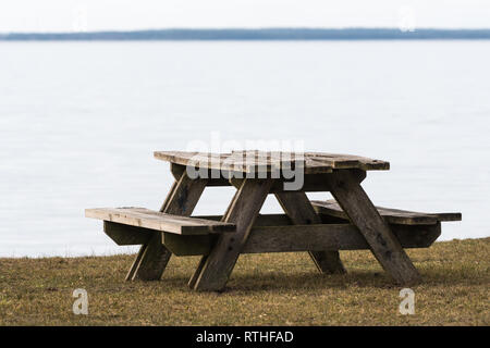 Table et bancs en bois patiné par la côte avec de l'eau calme Banque D'Images