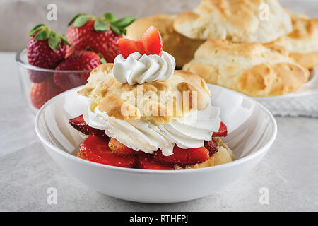 Fraisinette dans des bol blanc avec crème fouettée et garni d'une fraise en tranches. Bol de fraises dans le fond d'une plaque Banque D'Images