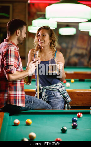 Jeune femme souriante de flirter avec l'homme au cours de jeu de billard Banque D'Images