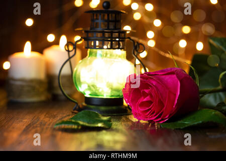 Rose rouge et de la lanterne avec des lumières, des bougies sur une table en bois. Concept romantique Banque D'Images