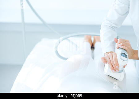 Séance de massage gpl dans focus. Les mains du thérapeute holding outil lipomassage. Close up shot intérieur avec beaucoup de couleur blanche Banque D'Images