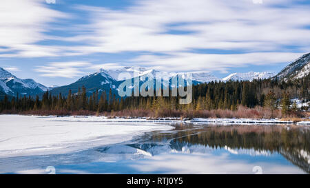 Lever du soleil sur les lacs Vermilion près de Banff, en Alberta, au Canada avec les montagnes environnantes reflétée dans la glace et l'eau. Banque D'Images