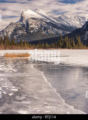 Lever du soleil sur les lacs Vermilion près de Banff, en Alberta, au Canada avec les montagnes environnantes reflétée dans la glace et l'eau. Banque D'Images