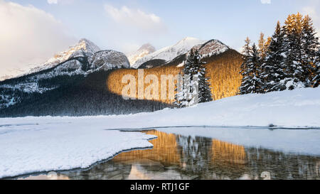 Aube dorée du soleil sur la forêt et les montagnes au-dessus de Lake Louise qui reflète dans le lac, le parc national Banff, Candaian Rocheuses, Alberta, Canada Banque D'Images