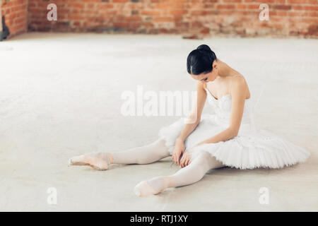 Danseur de Ballet est fatigué après l'entraînement. jeune fille assise avec tête de courbure sur le sol lors de l'épuisement. des cours de ballet, de la fatigue, des difficultés à Banque D'Images