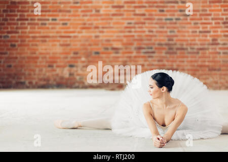 Belle ballerine faisant le grand écart en position allongée sur le sol dans le loft studio. copie espace, fille avec les jambes tendues au repos dans le studio Banque D'Images