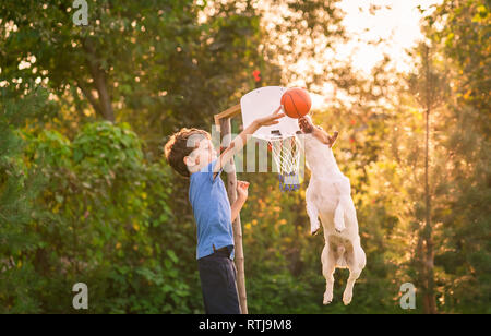 Enfant jouant au basket-ball avec son chien dans le jardin Banque D'Images