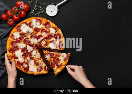 Woman taking morceau de pizza au pepperoni, à l'aide d'une spatule Banque D'Images