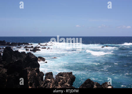 De superbes nuances de bleu de l'océan Pacifique en opposition contre un rivage rocailleux de lave noire à Paupahoehoe Point dans New York, USA Banque D'Images