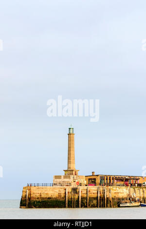 Stone concerte phare sur Fin de la jetée du port de Margate. À marée basse, la pêche bateau amarré à l'embarcadère. Ciel couvert ciel gris. L'espace négatif. Banque D'Images