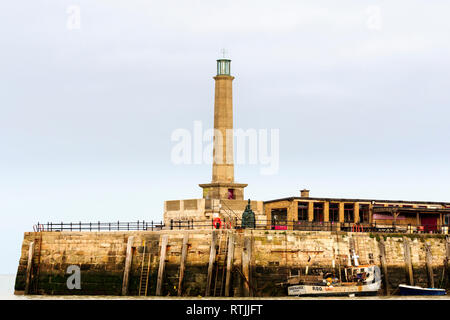 Stone concerte phare sur Fin de la jetée du port de Margate. À marée basse, la pêche bateau amarré à l'embarcadère. Ciel couvert ciel gris. Banque D'Images