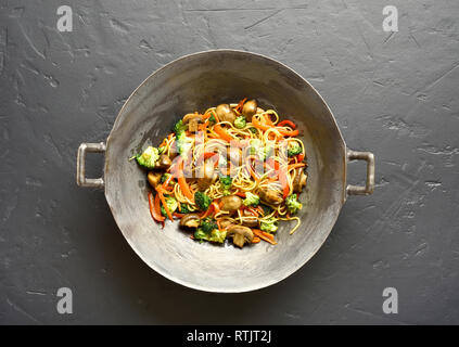 Nouilles Udon sautés avec légumes en wok casserole sur fond noir en noir. Haut de la vue, télévision lay Banque D'Images